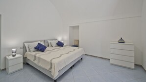 Un dormitorio con cama, mesita de noche, cómoda y lámpara.