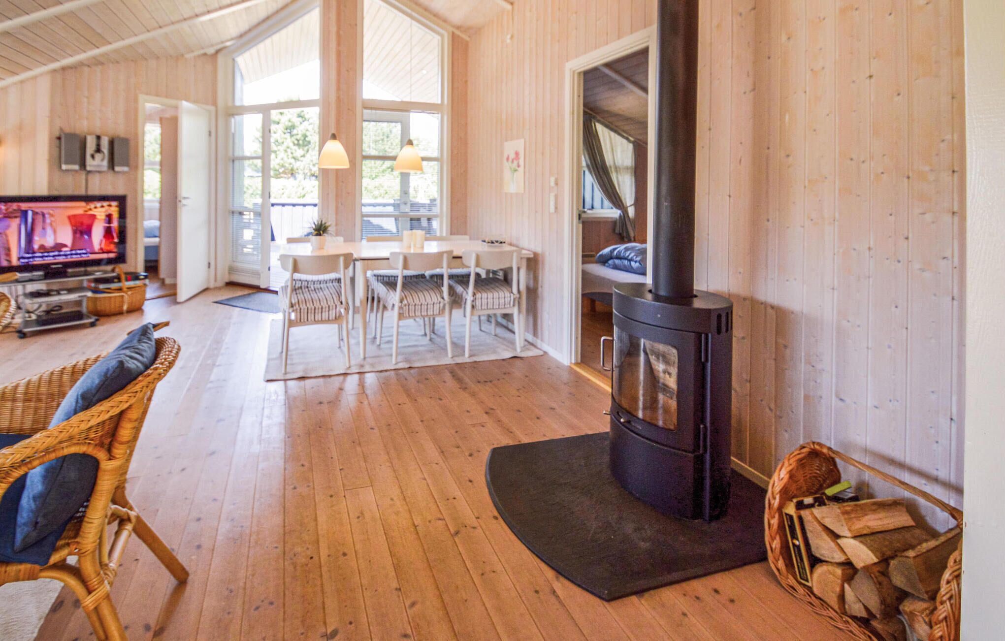 Una sala de estar acogedora con detalles de madera, una chimenea, una zona de comedor con mobiliario blanco y un televisor.