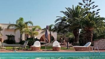 Relax by the pool surrounded by lush greenery and a palm tree.