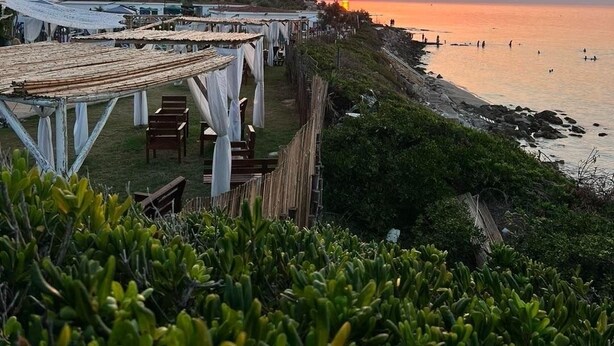 Ein Küstenbereich mit Sonnenuntergangsblick, Außenbestuhlung und Meerblick.