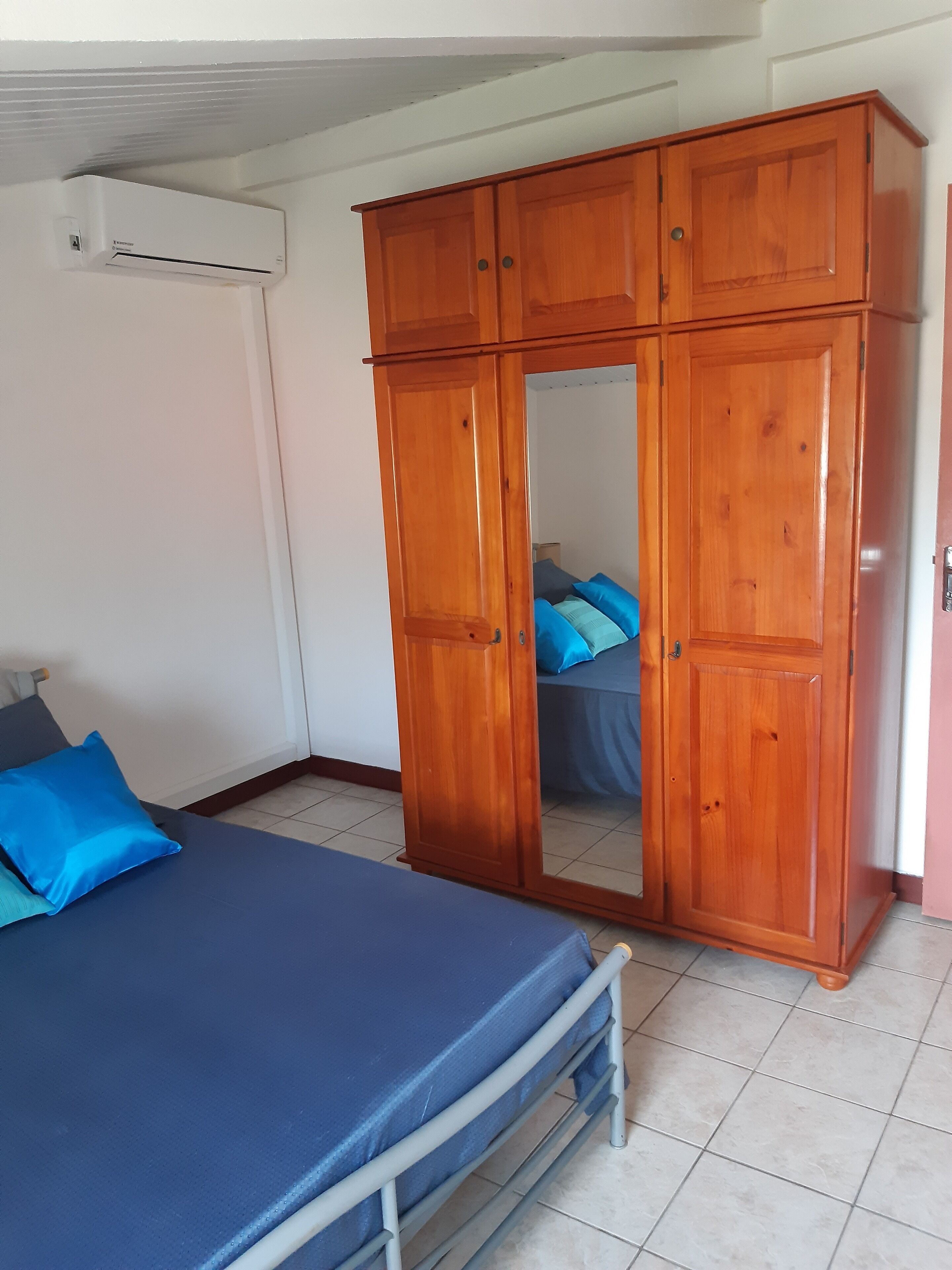 Un dormitorio con cama, armario y aire acondicionado.