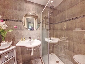 A bathroom with two sinks, a shower enclosure, and a mirror.