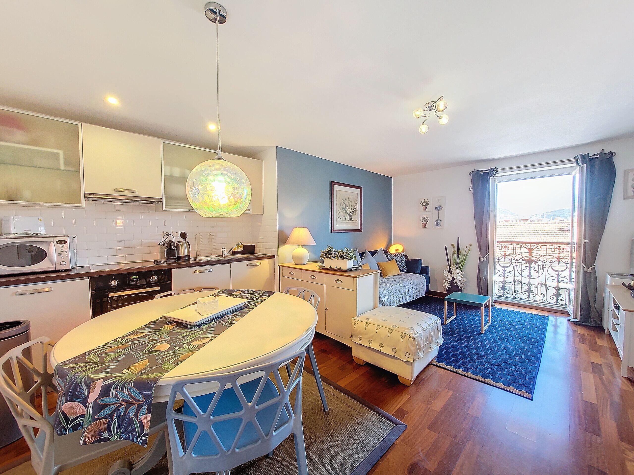 A compact living space with a kitchen, dining area, and a balcony with a view.