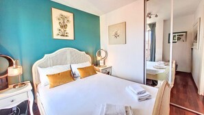 Ein Schlafzimmer mit einem Bett, Nachttischen, einem Spiegel und Kunstwerken an den Wänden.