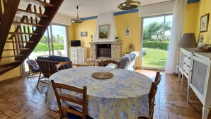Un comedor con una mesa redonda, sillas, chimenea y una escalera.