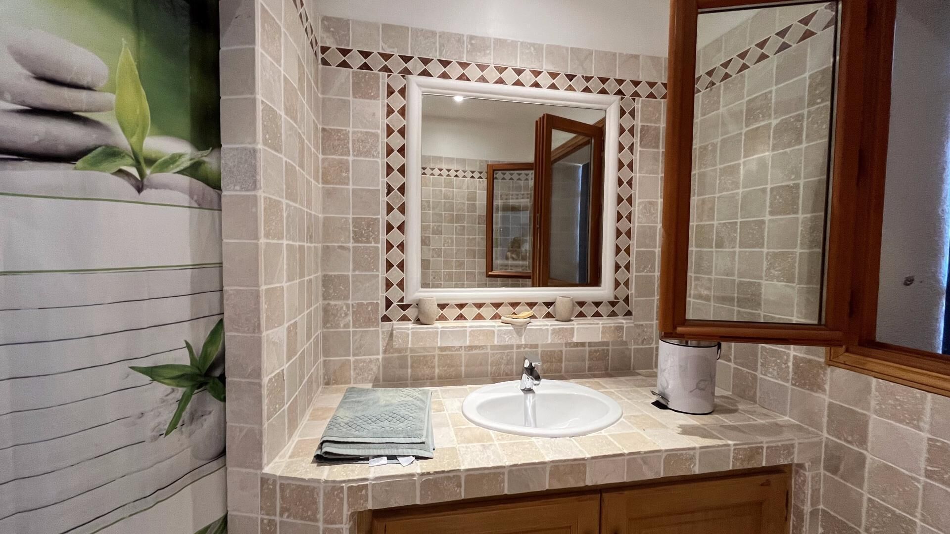 Een badkamer met een wastafel, spiegel en betegelde wanden.