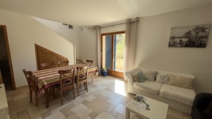 Una sala de estar con un sofá, una mesa de comedor con sillas, una mesa de centro y un cuadro en la pared.