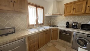Una cocina con alacenas de madera, lavavajillas, estufa, microondas y lavadora.