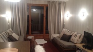 Un accogliente soggiorno con un tavolo in legno, due divani, una televisione su un mobile e un piccolo tavolino rotondo.