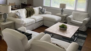 A modern living room with a sectional sofa, two armchairs, a coffee table, and a dining area.