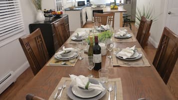 Une table à manger dressée pour six personnes, avec des assiettes, des verres et une bouteille de vin.