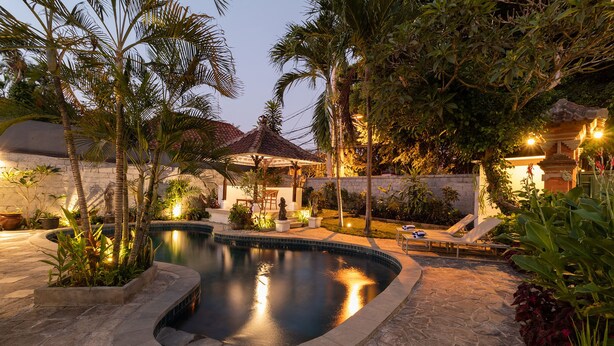 A private pool area with a stone deck, lounge chairs, and a small waterfall feature. - Villa Miracle (Denpasar)