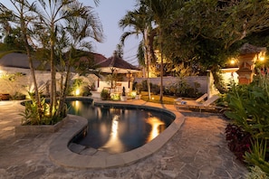 A private pool area with a stone deck, lounge chairs, and a small waterfall feature. - Villa Miracle (Denpasar)
