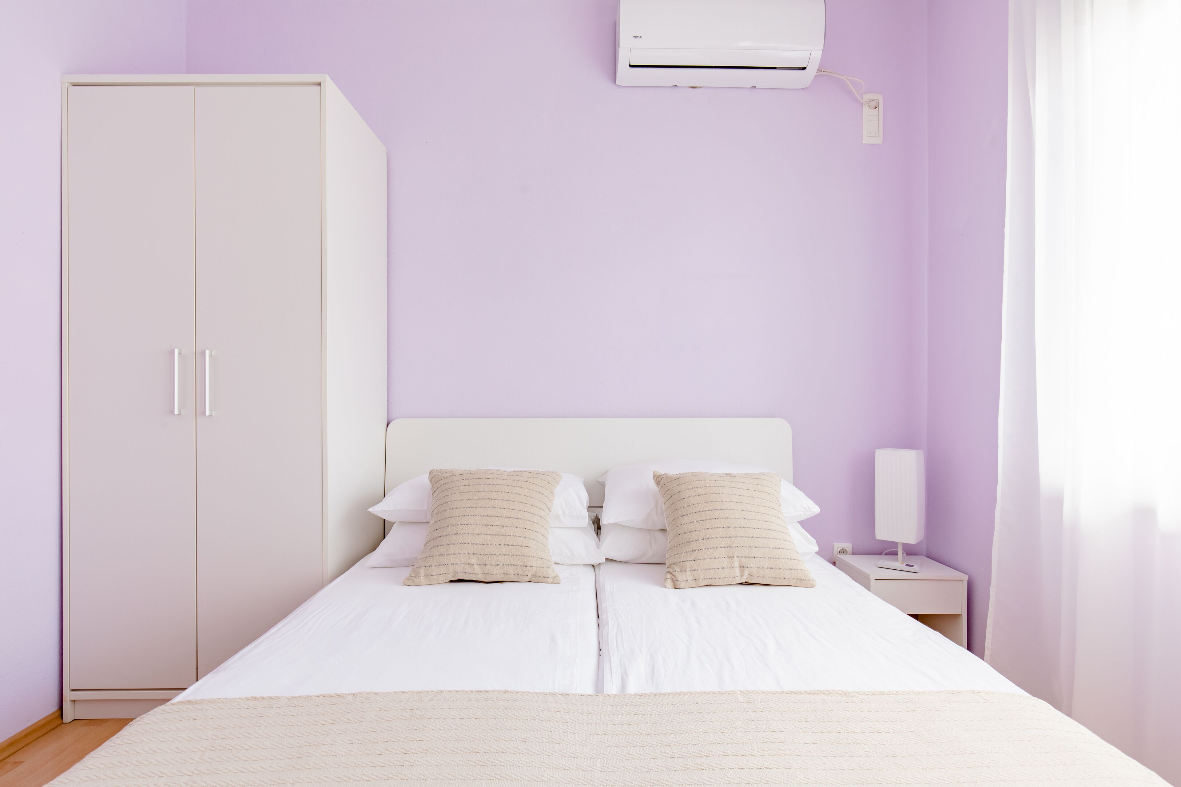 Een slaapkamer met een bed, twee nachtkastjes, een kledingkast en een airconditioning.