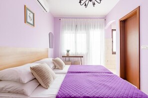 A bedroom with a bed, a bedside table, a window with curtains, and a door. - Apartments Mara (Kastela)