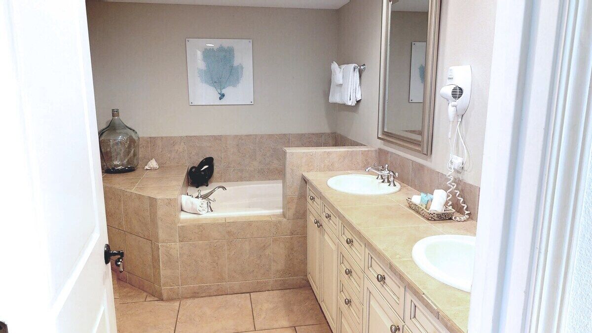Une salle de bain avec une baignoire, deux lavabos, un sèche-cheveux et un porte-serviettes.