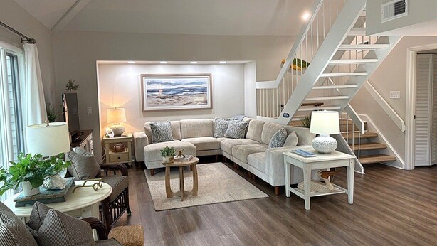 A living room with a sectional sofa, a coffee table, a side table, and a staircase. - Popular Spinnaker Beach House! Close to Beach! Amenity access included! (Seabrook Island)