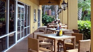 An outdoor patio with wicker furniture and glass doors leading to a garden area. - 3Bed ★ 2.5Bath ★ Gated Resort ★ Private & Clubhouse Pools ★ 5 Miles to Disney (Kissimmee)