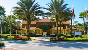 A hotel entrance with a red-tiled roof, palm trees, and flags. - 3Bed ★ 2.5Bath ★ Gated Resort ★ Private & Clubhouse Pools ★ 5 Miles to Disney (Kissimmee)