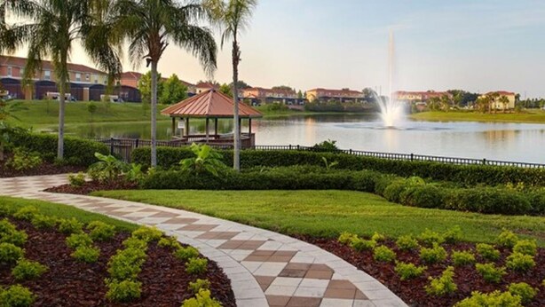 A landscaped pathway leading to a gazebo by a lake, with a fountain in the background. - 3Bed ★ 2.5Bath ★ Gated Resort ★ Private & Clubhouse Pools ★ 5 Miles to Disney (Kissimmee)