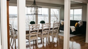 A dining area with a table and chairs, a chandelier, and a view of the outdoors.