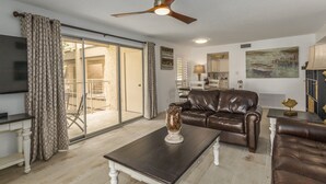 A living room with a brown leather sofa, a coffee table, and a ceiling fan.