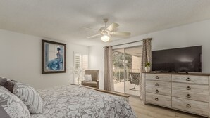 A bedroom with a bed, a dresser, a television, and a ceiling fan.