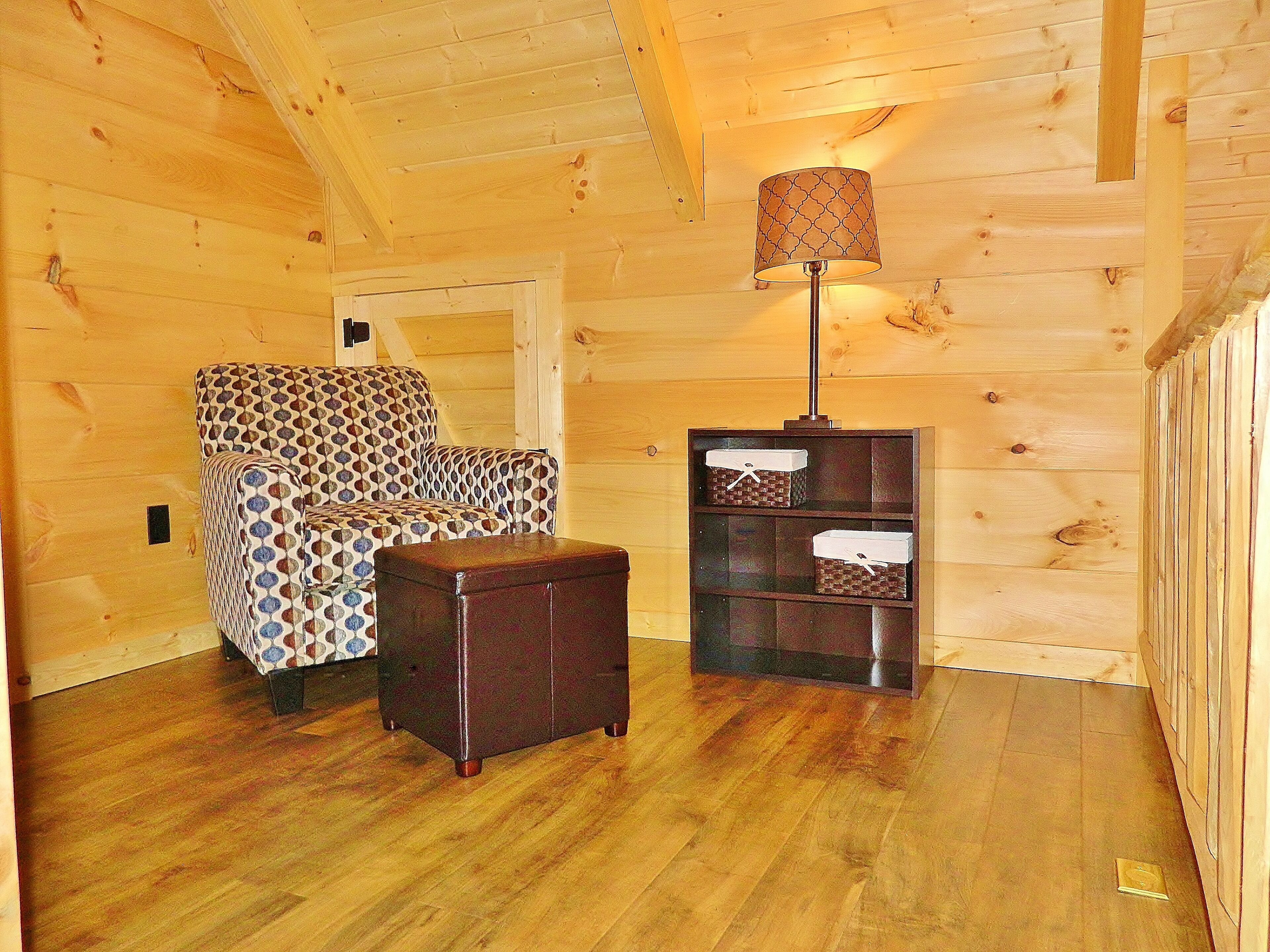 Una habitación acogedora con un sofá estampado, un mueble de madera pequeño y una lámpara de pie.