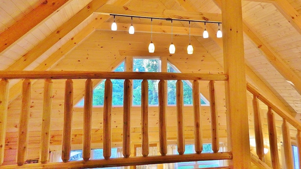 A wooden interior with a high ceiling, exposed beams, and a series of hanging lights.