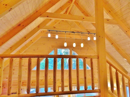 Un interior de madera con techo alto, vigas a la vista y varios candelabros colgantes.