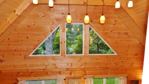 A wooden cabin with a high ceiling, triangular windows, and hanging pendant lights.