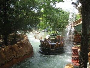 A water ride with a circular raft, surrounded by trees and a river.