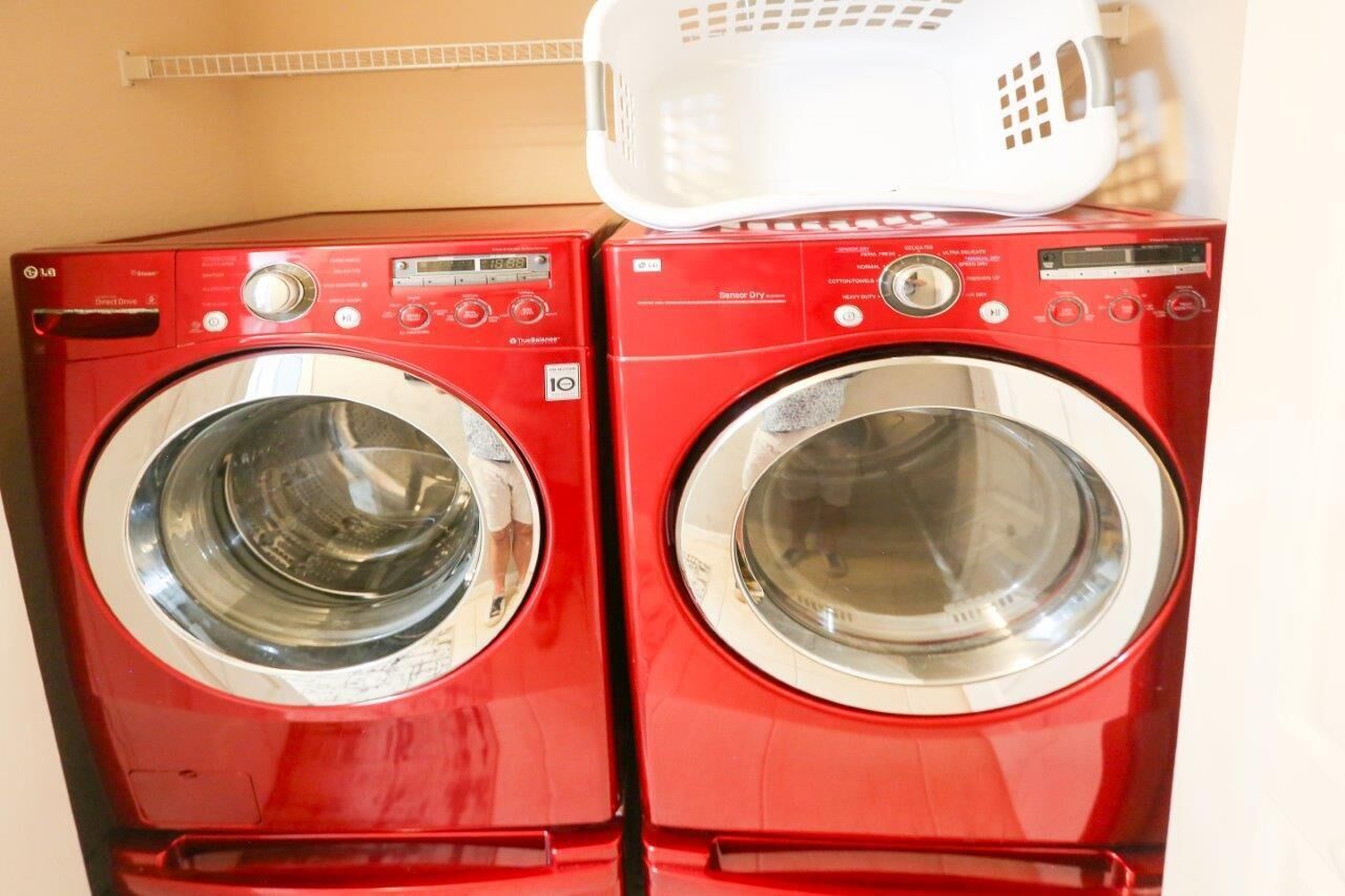 Two red front-loading washing machines stacked on top of each other.