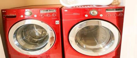 Two red front-loading washing machines stacked on top of each other.