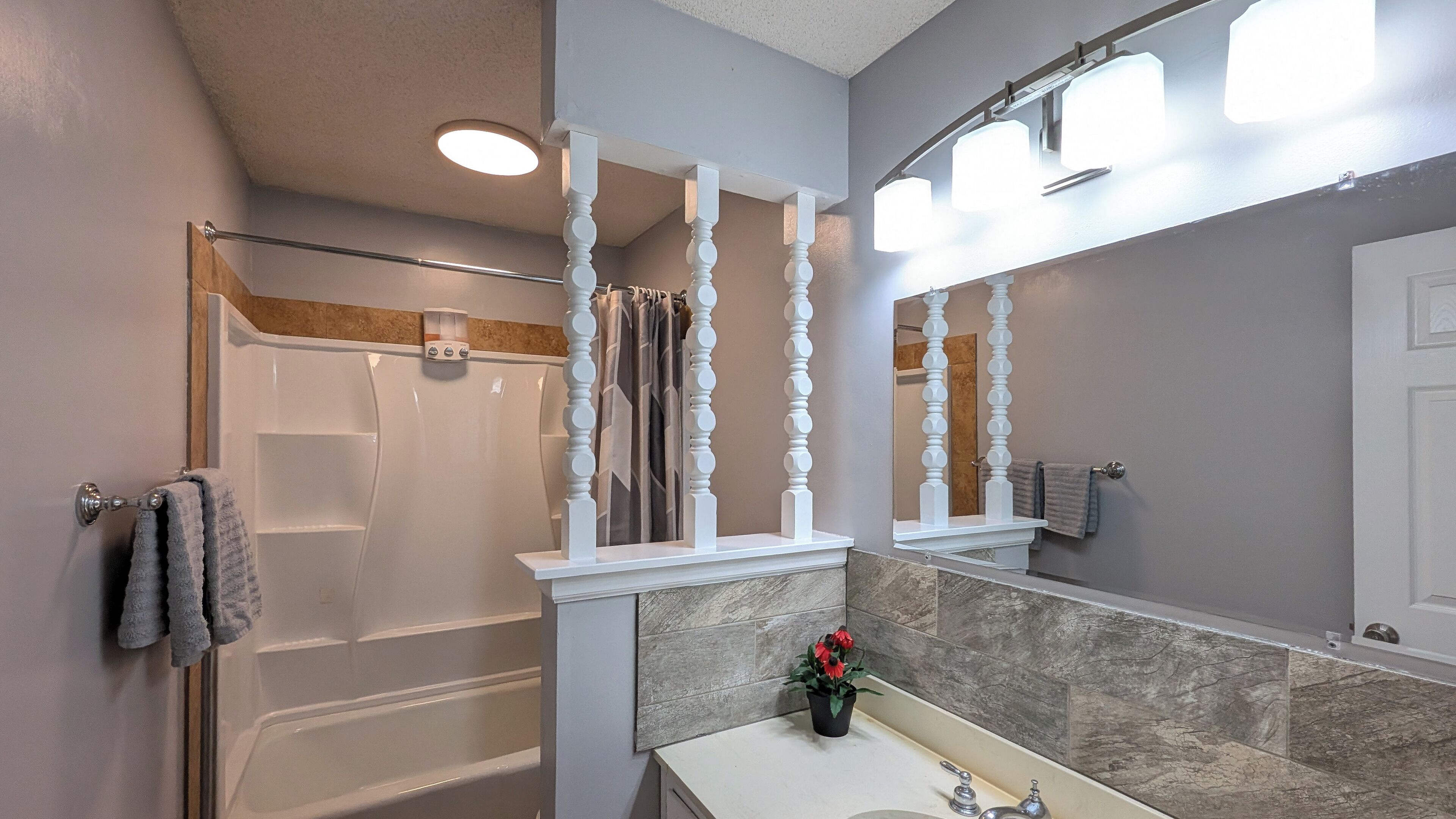 A bathroom with a bathtub, a shower, a sink with a mirror, and a towel rack.