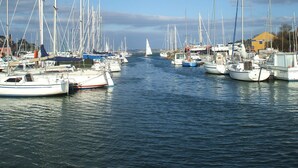 A marina with multiple sailboats docked, a small sailboat in the distance, and buildings in the background. - Spacious farmhouse ,wheelchair accessible , close to stunning beaches . (Landudec)
