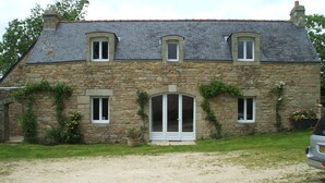 A stone house with a tiled roof, a central entrance with glass doors, and a gravel driveway. - Spacious farmhouse ,wheelchair accessible , close to stunning beaches . (Landudec)