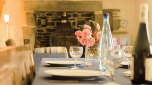 A dining table set with plates, glasses, and a bottle of wine, with a vase of flowers in the center. - Spacious farmhouse ,wheelchair accessible , close to stunning beaches . (Landudec)