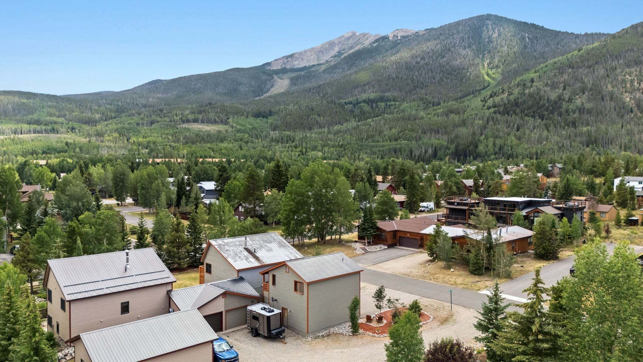 A residential area with houses, a small building with a garage, and a mountain in the background.