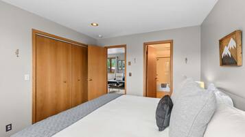 Un dormitorio con una cama grande, un armario de madera y vista a otra habitación.