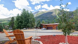 A wooden chair and table in a landscaped area with a mountain backdrop.