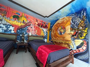 A room with a mural, a bed, a chair, and a small table. - Chill Out Bar and Bungalows (Krabi)
