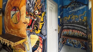 Een kamer met een muurschildering van een draak, een bed en een deur.