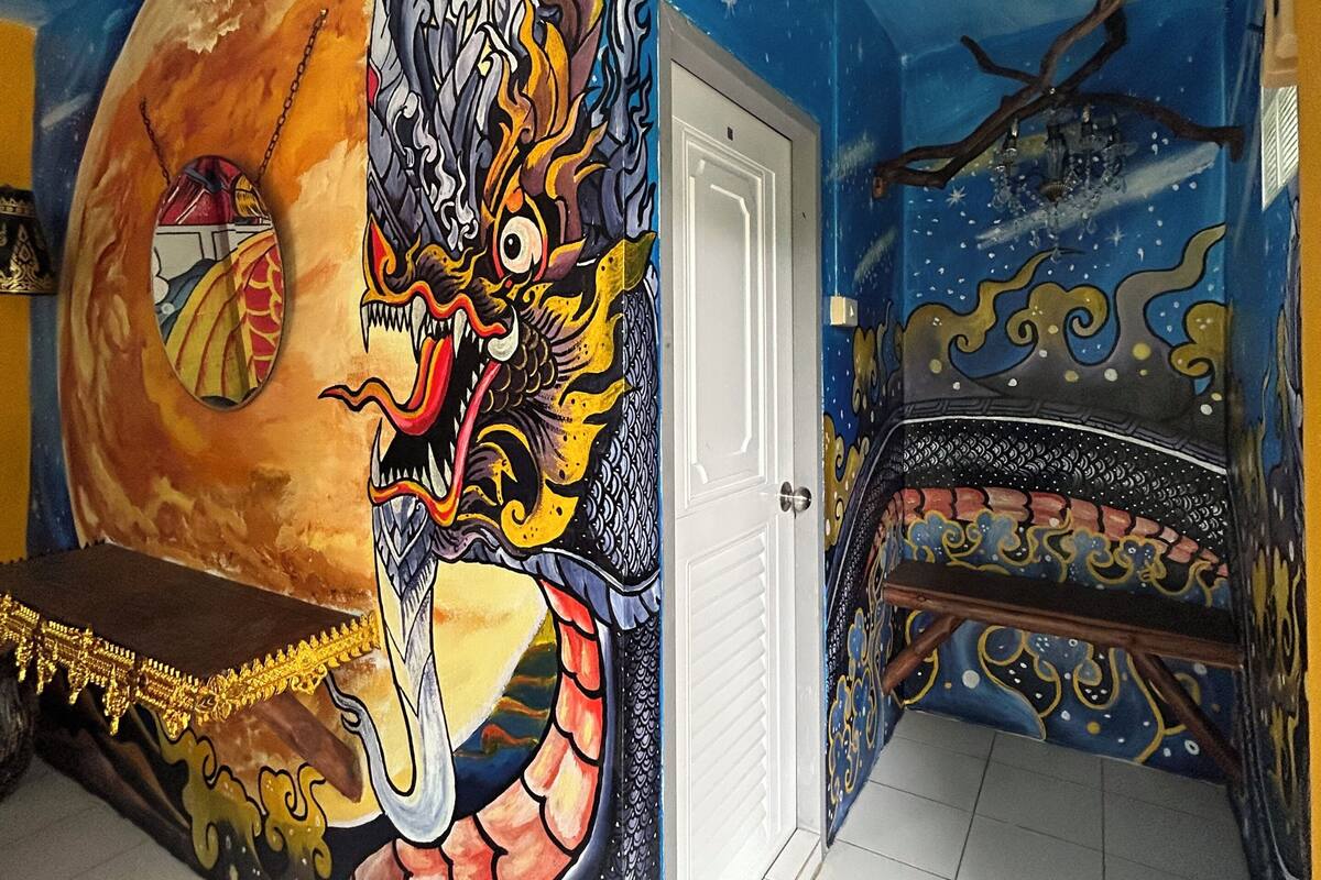 Une pièce avec une fresque représentant un dragon, un lit et une porte.