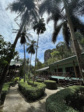 A pathway leading to a building with a balcony, surrounded by palm trees and greenery. - Chill Out Bar and Bungalows (Krabi)