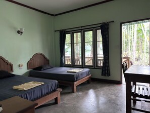 A room with two beds, a table, and a window with curtains.