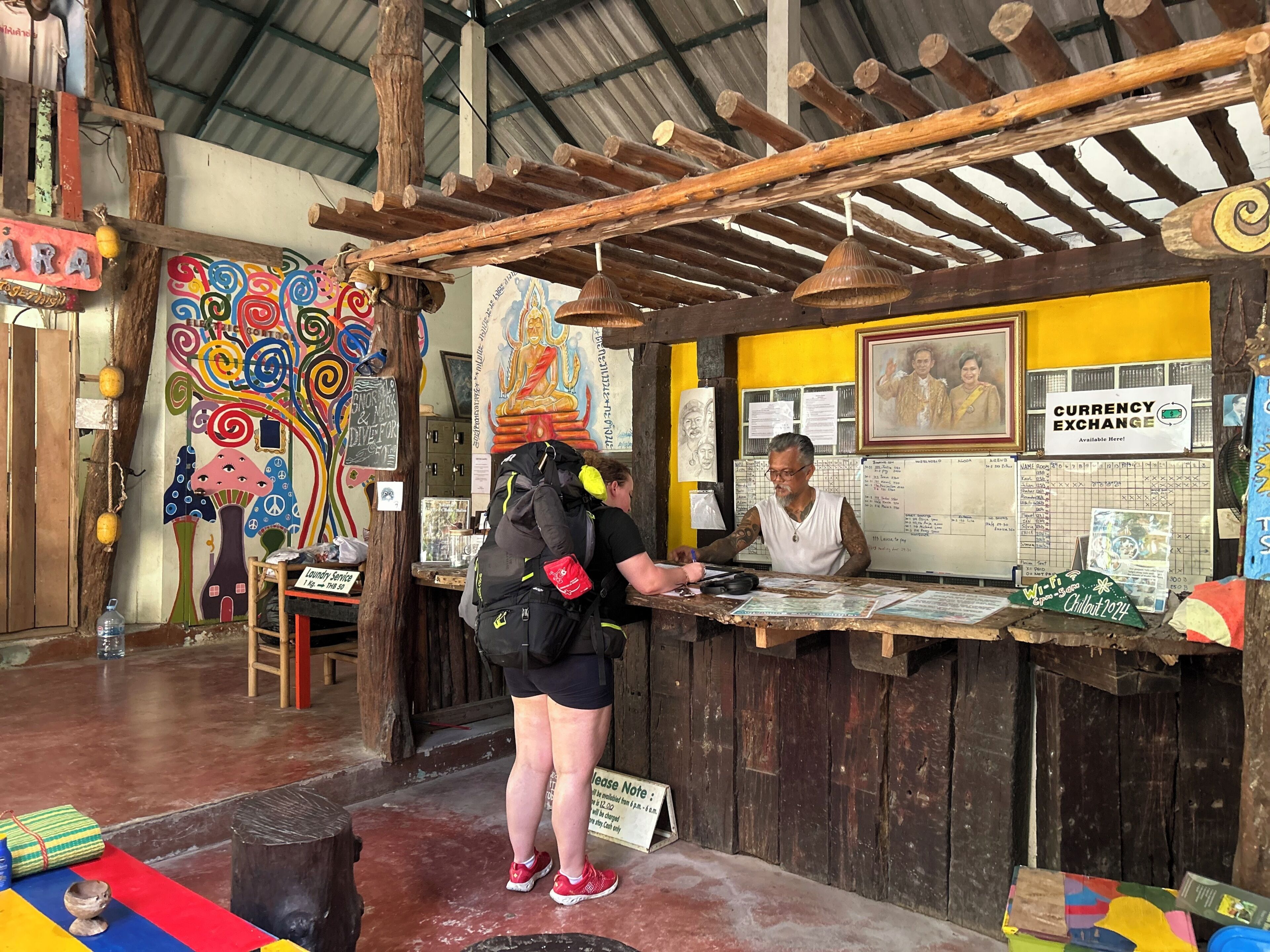 A rustic currency exchange booth with wooden beams, a colorful mural, and a sign for currency exchange.