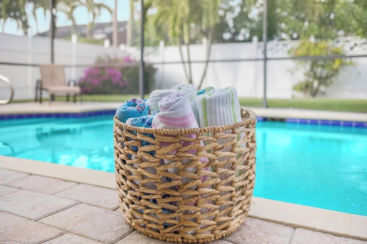A wicker basket with towels by a pool.