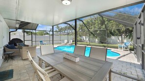 Un patio techado con piscina, mobiliario exterior y vista al jardín trasero.