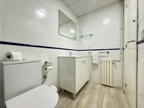 Ein Badezimmer mit Toilette, Waschbecken, Spiegel und Handtuchhalter.